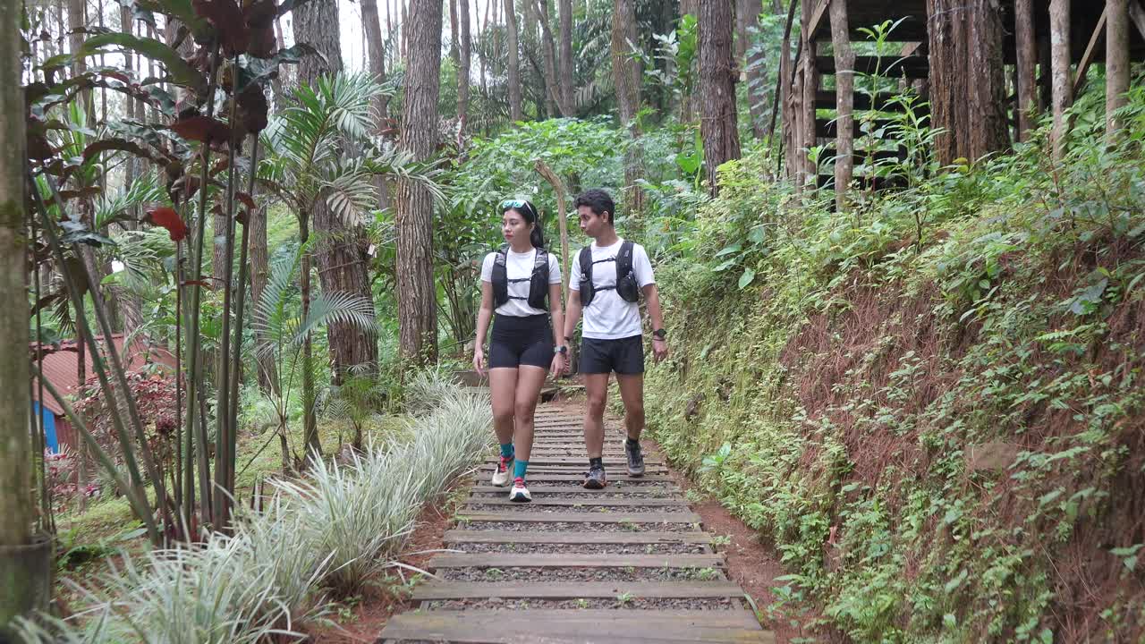 Asian couple walking on forest trail path during outdoor adventure in Indonesia