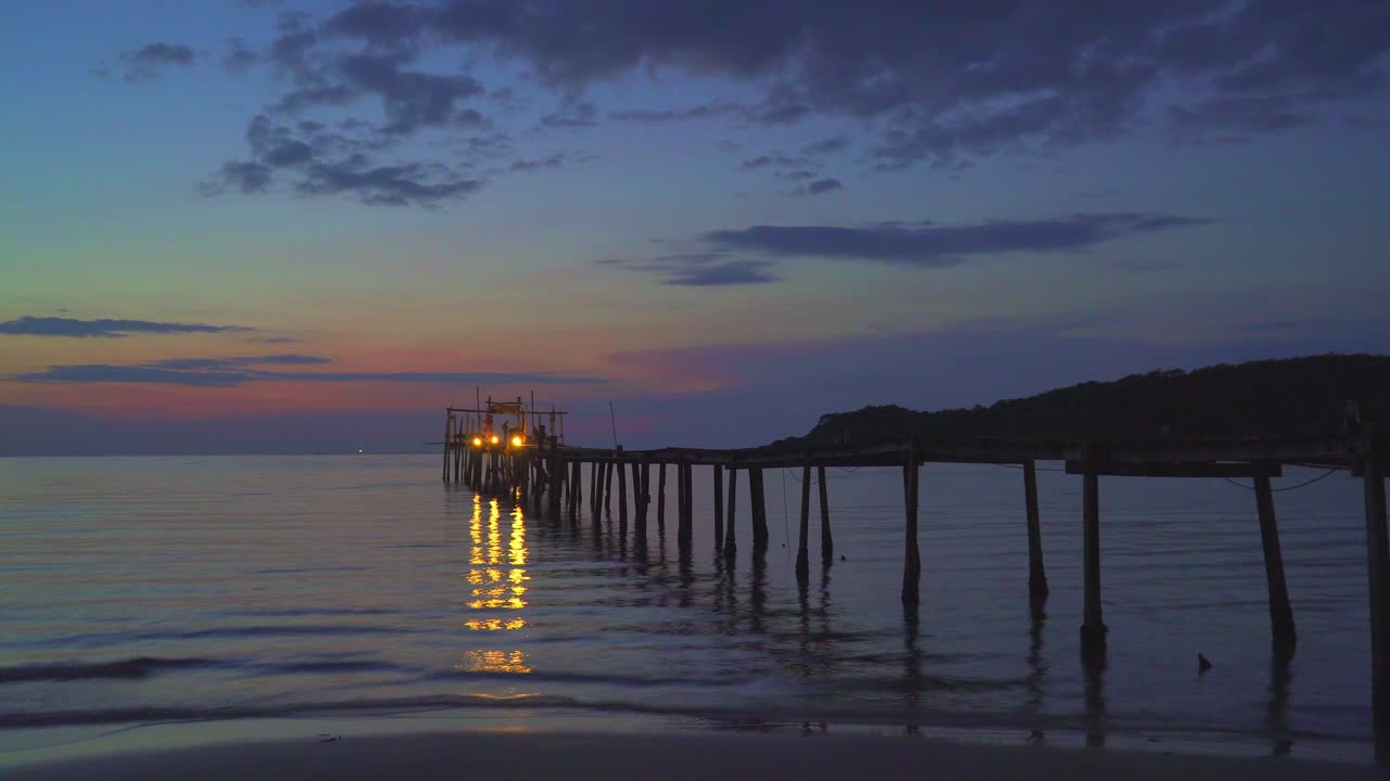 Sunset over a pier on a tropical beach