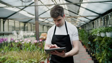 Tech-Savvy-Inventory-Management-at-a-Flower-Shop.-A-young-guy-in-a-black-apron-as-an-employee-of-a-specialized-store-makes-an