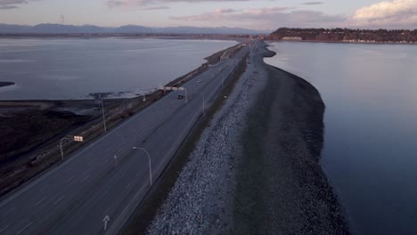 Tsawwassen-ferry-bc-terminal,-Vancouver-Canada,-aerial-of-scenic-highway-over-the-ocean-with-cars-and-truck-during-sunset