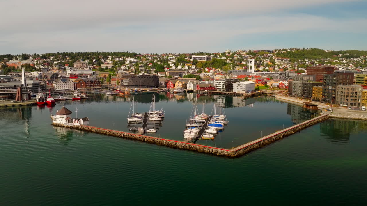 Lotniczy widok z drona na port i przystań w Tromsø w Norwegii w słoneczny letni dzień. Ukazano łodzie, budynki nabrzeżne i centrum miasta.