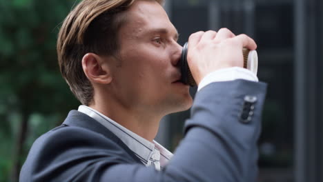 portrait successful businessman walking downtown area drinking coffee alone.