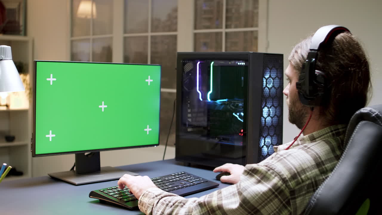 Gamer playing on computer with green screen