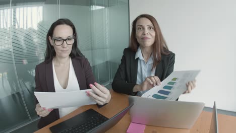 smiling caucasian businesswomen greeting and showing charts