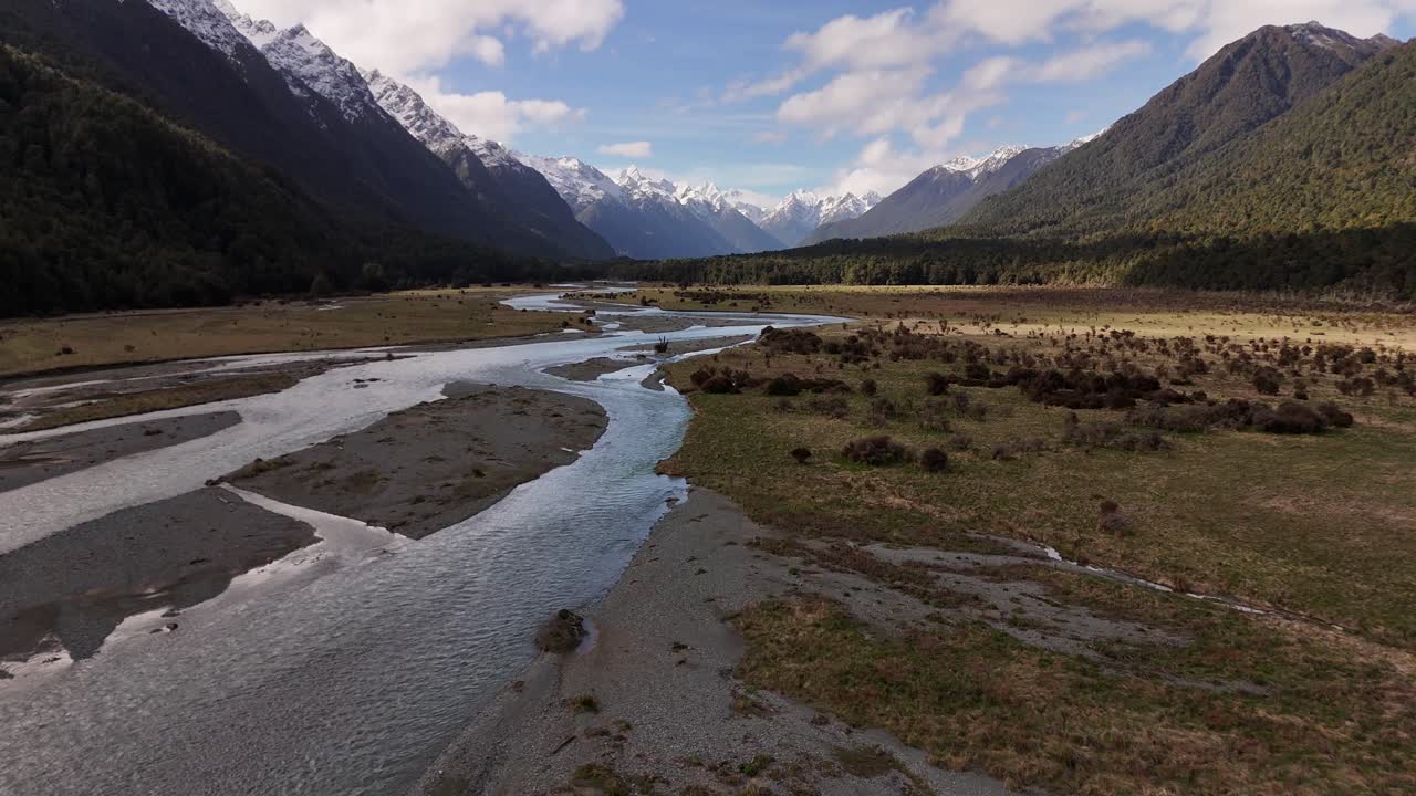 Vista cinematografica da drone a bassa quota che sorvola il fiume Eglinton in direzione di Milford Sound. L'acqua limpida scorre attraverso una valle incorniciata da montagne innevate. Nuova Zelanda