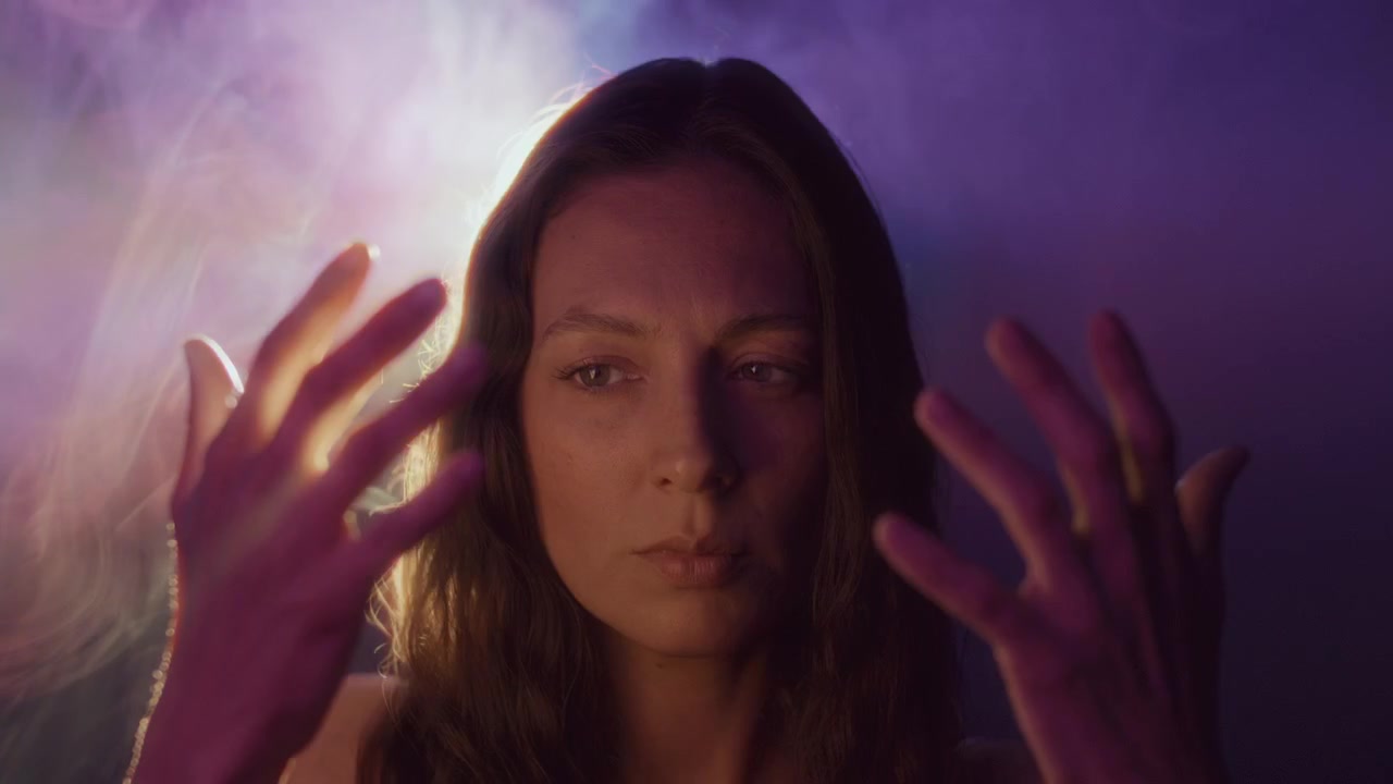 Donna misteriosa che guarda le sue mani sotto luce al neon e fumo