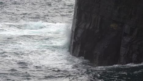 las olas chocan implacablemente contra las rocas masivas en el océano