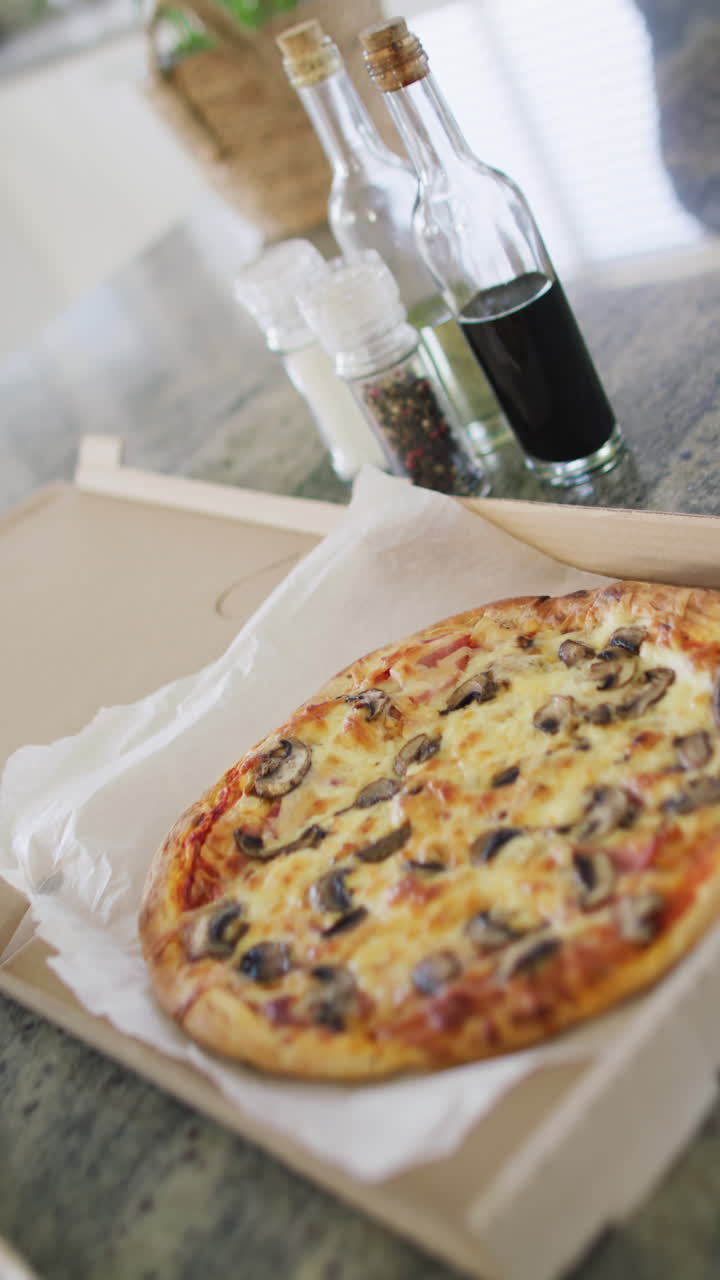Vertical video of take away pizza on kitchen worktop in slow motion