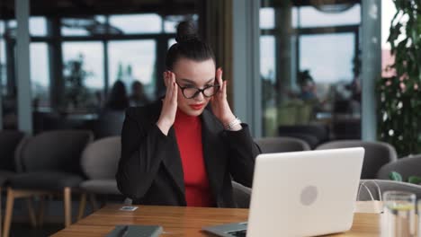 beautiful,-stern-young-woman-in-business-attire-argues-and-gestures-with-her-hands-during-a-video-call-on-a-laptop,-sitting-in-an-office