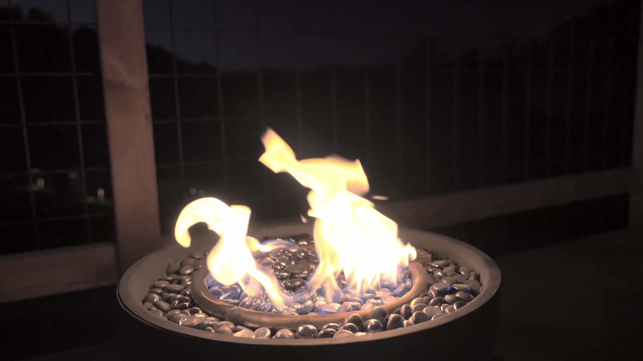 Modern gas-powered fire pit, featuring decorative glass marbles that shimmer in the glow of the flames