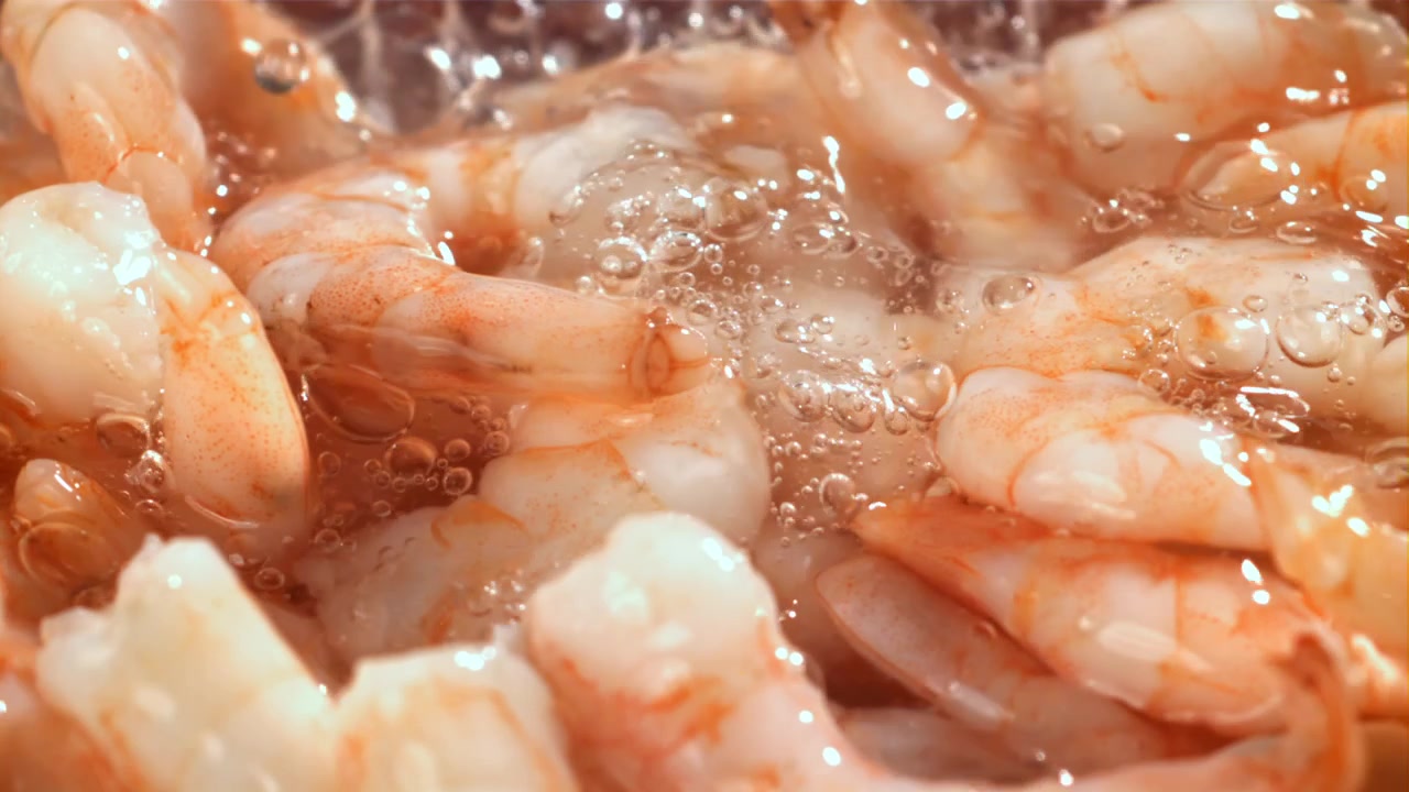 Gamberi sgusciati che schizzano nell'acqua bollente