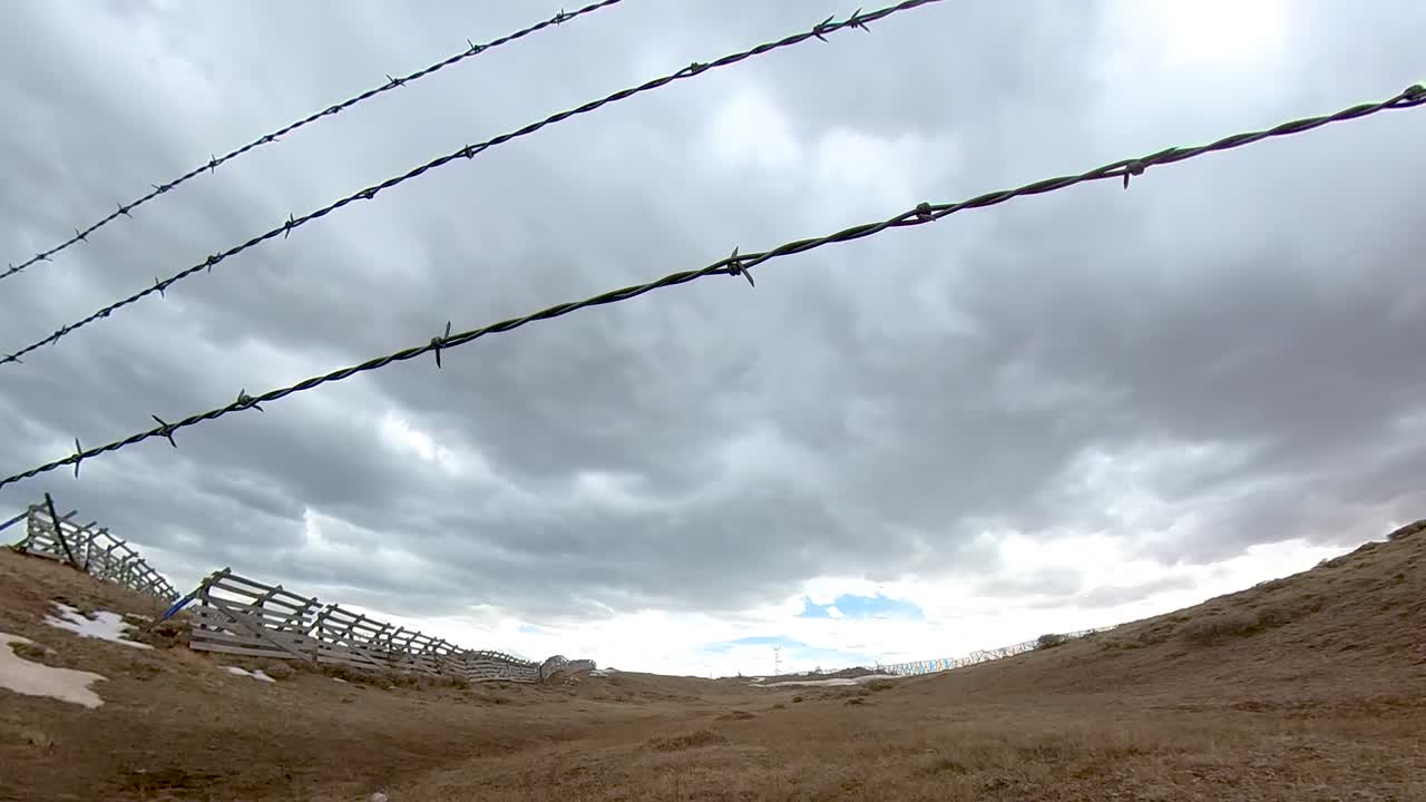 los cielos tormentosos retumban en un paisaje del viejo oeste con cercas de alambre de púas en primer plano.