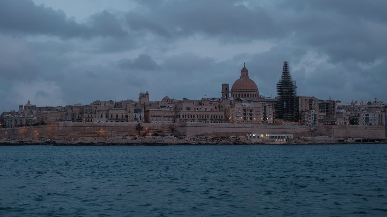 dramático lapso de tiempo del paisaje urbano de valletta durante la puesta de sol con nubes pesadas pasando, malta