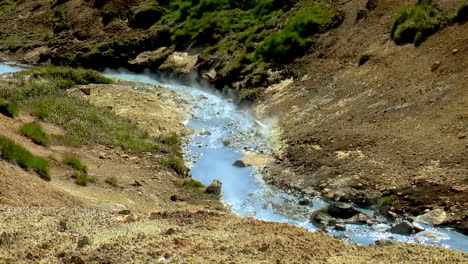 slow motion footage of hot, boiling river with smoke from steaming hot springs in seltun geothermal area in iceland