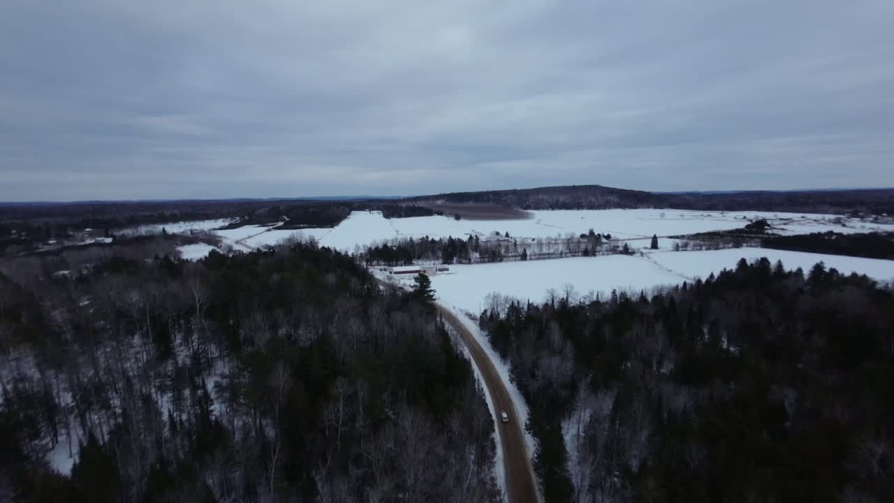 Aerial View of a Snowy Road Through a Winter Forest