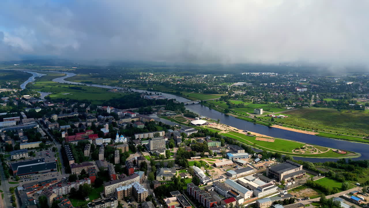 Establishing aerial shot over the city next to river with clouds passing slowly