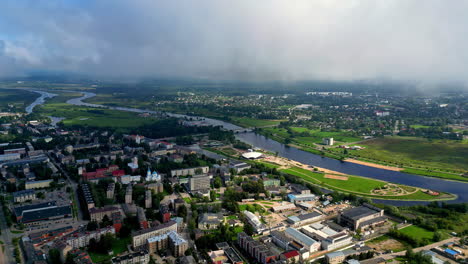 establishing aerial shot over the city next to river with clouds passing slowly
