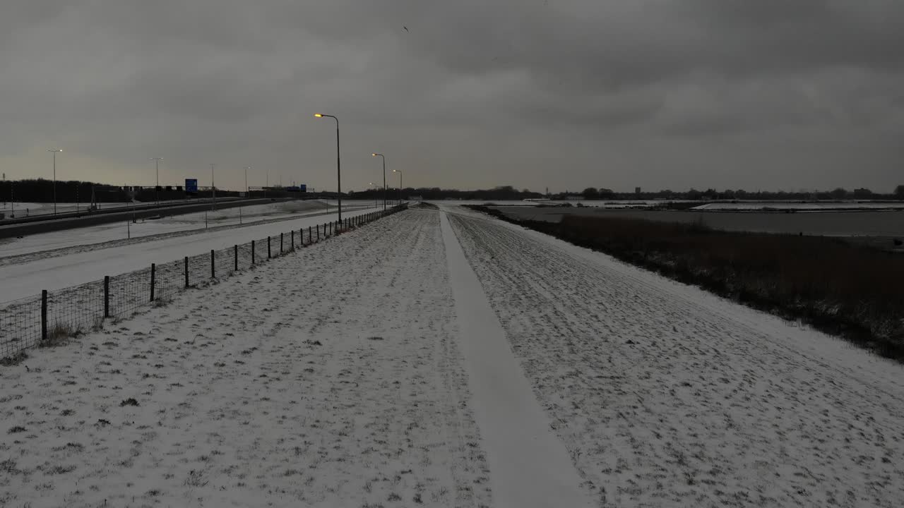 남자는 흐린 아래 울타리와 함께 설원 한가운데를 걷는다