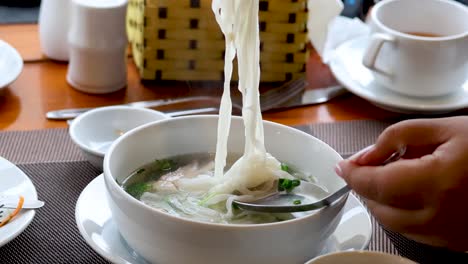 person eating noodle soup at a dining table