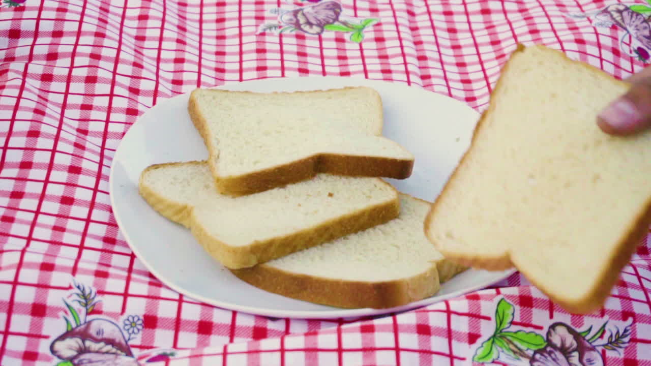 Hand take in slow motion a slice bread from a bunch of other slice breads outside in the morning camping in the nature