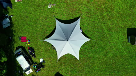 an aerial shot of a white tent mounted on a lawn and vans parked beside it