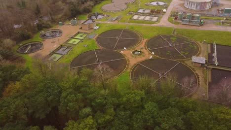 planta de tratamiento de aguas residuales de aguas residuales en el bosque en thetford, norfolk - disparo de vuelo aéreo de drones timelapse en círculos