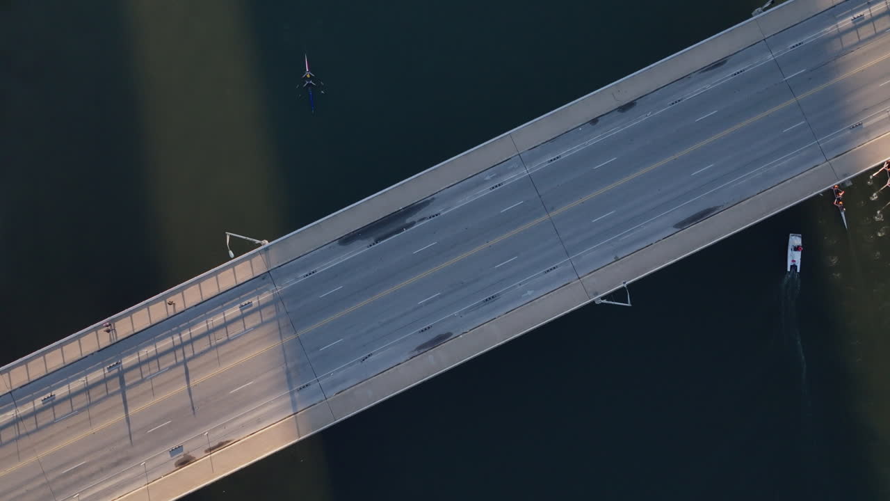 다리를 가로지르는 자동차와 자전거 타는 사람들의 공중 촬영과 조용한 강 장면, 오르는 배, 도시 운동과 강변의 평온함의 매혹적인 혼합.