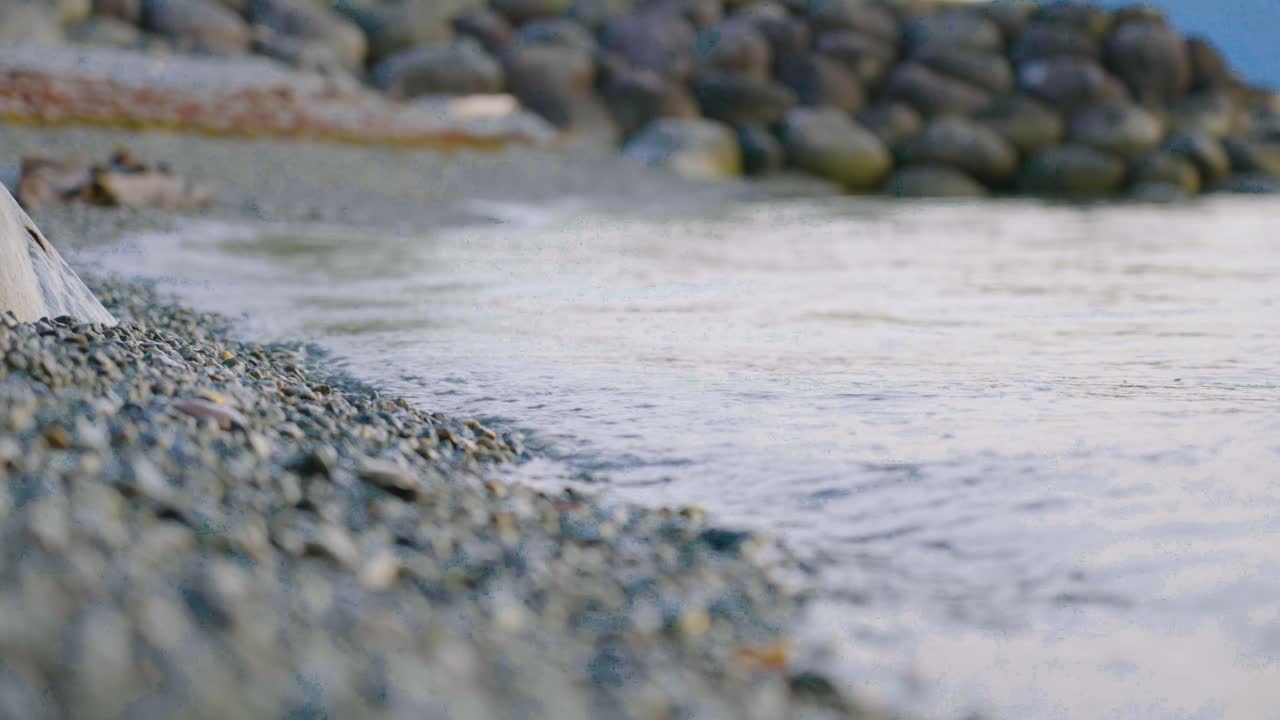 a close up of waves crashing on the beach shore on a warm sunny day in Lions Bay, British Columbia, Canada