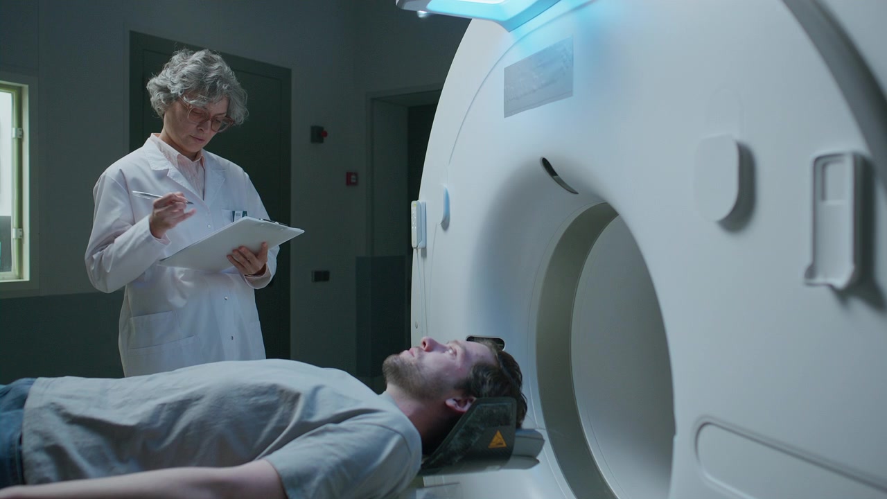 Medico che prende appunti e parla con un paziente prima di una procedura di TAC.