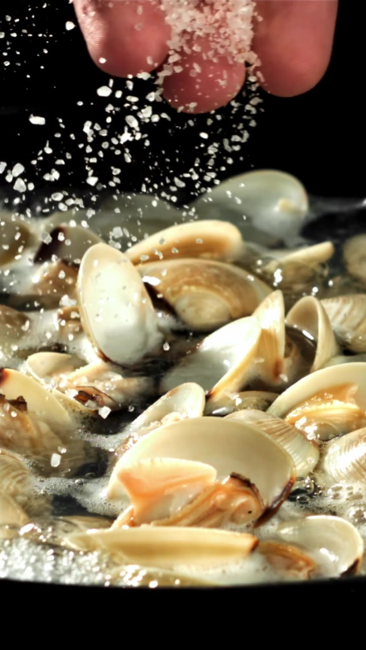 Slow Motion of Hand Sprinkling Salt on Cooking Clams