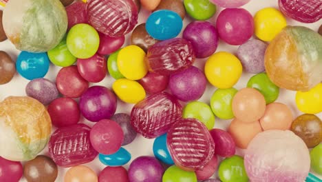 colorful dragee candies, lollipops, bonbons on white background, move in circle, top view close-up. summer bright texture studio shot for store, supermarket. mix of children's sweets made of sugar.