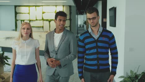 diverse colleagues in office hall. black man in suit walking in hall of office with coworkers showing place and talking in leisure