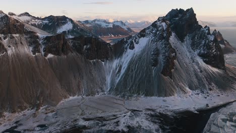 Drohnenaufnahme-Vom-Felsigen-Vestrahorn-Gipfel-Entfernt,-Wintersonnenuntergang-In-Stokksnes,-Island