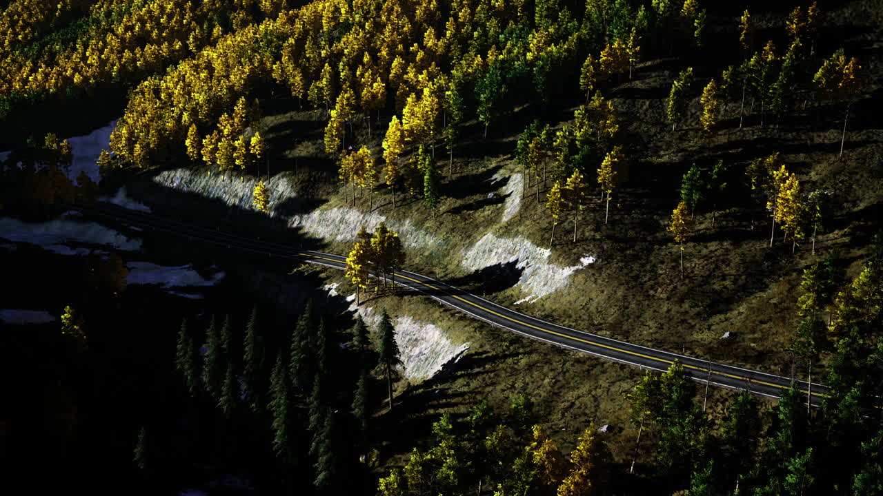 Road winding through autumn forest with vibrant foliage near a mountain