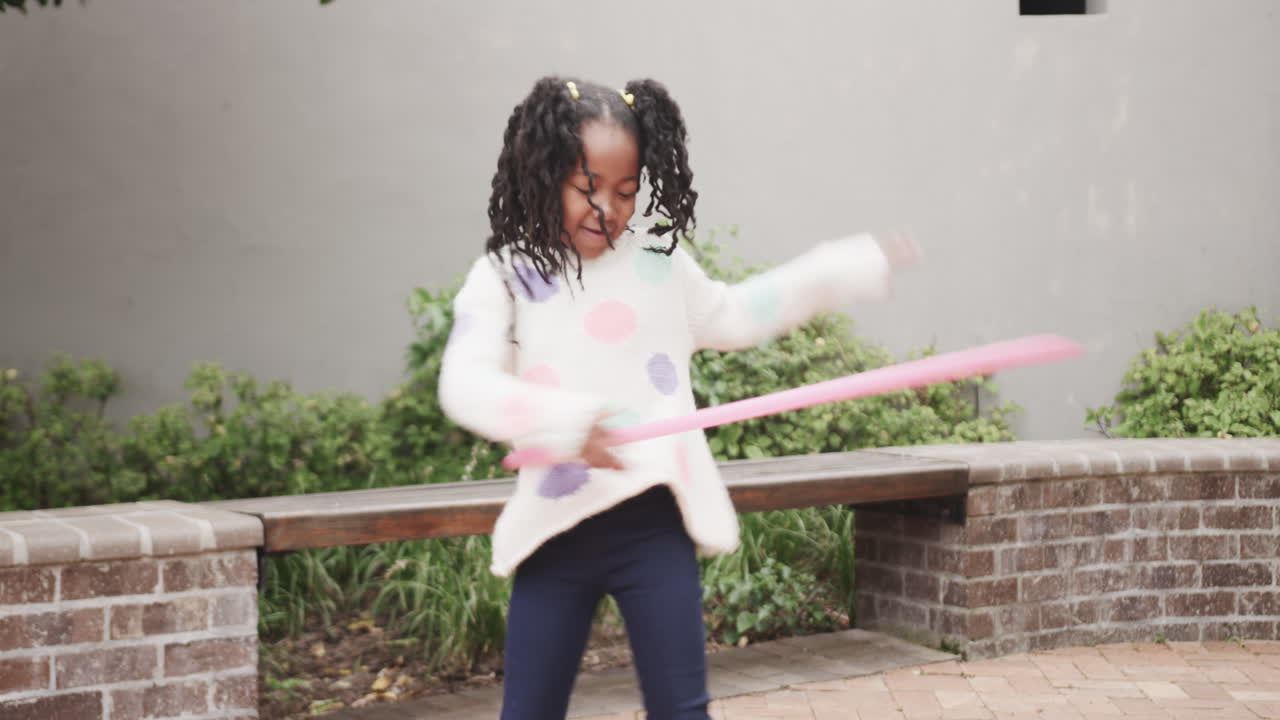 Ragazza che fa girare l'hula hoop all'aperto, divertendosi durante un momento di gioco attivo.