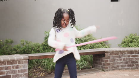 girl spinning hula hoop outdoors, having fun during active playtime