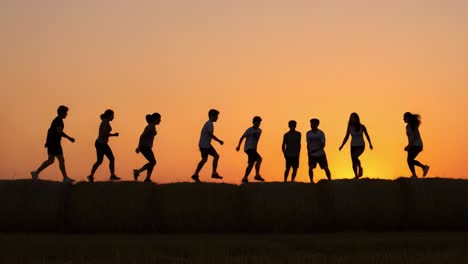 A group of energetic individuals joyfully leaping and running against a stunning sunset backdrop, capturing the essence of freedom and camaraderie in a vibrant outdoor setting