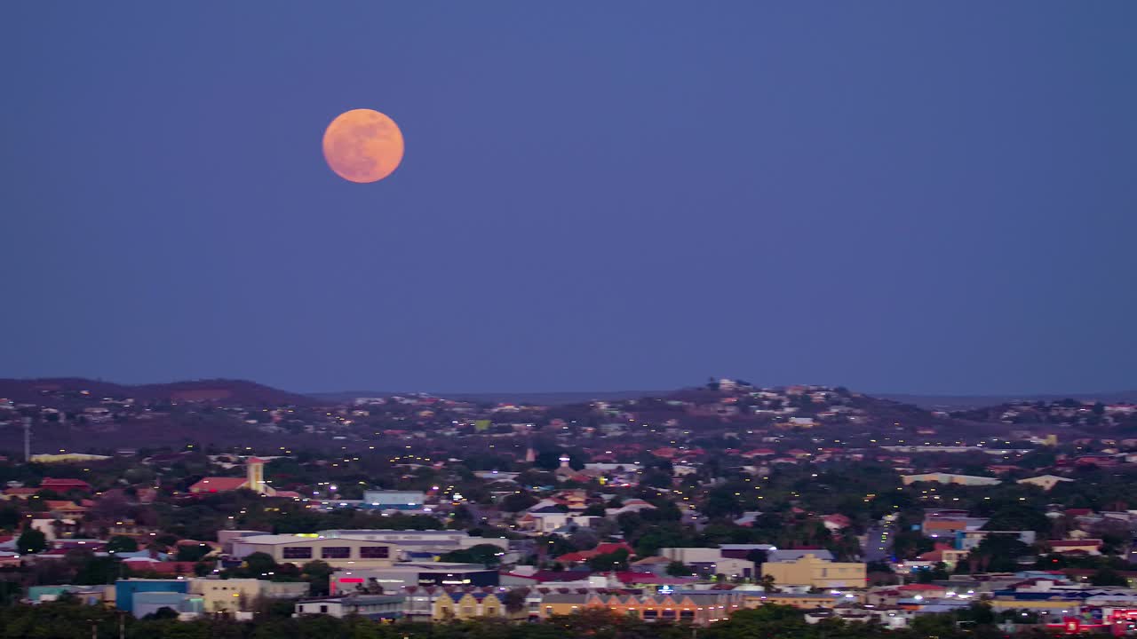 윌렘스타드 외 ⁇ 의 쿠라카오 산맥에서 스카이라인 산업 구역을 가로질러 완전한 슈퍼문, 보라색 하늘에 대한 빨간색