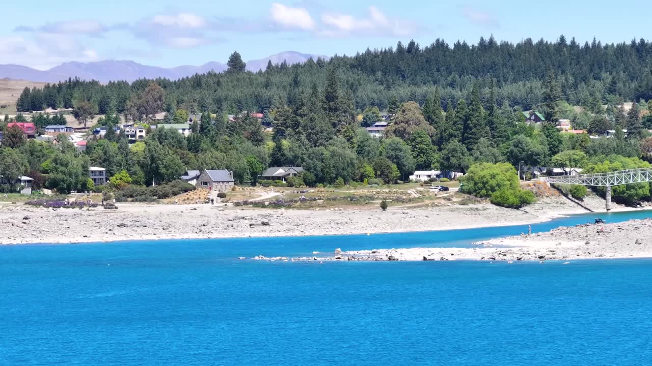 Aerial view of tourist attraction of small church on lakefront lake Tekapo, New Zealand, sunny day