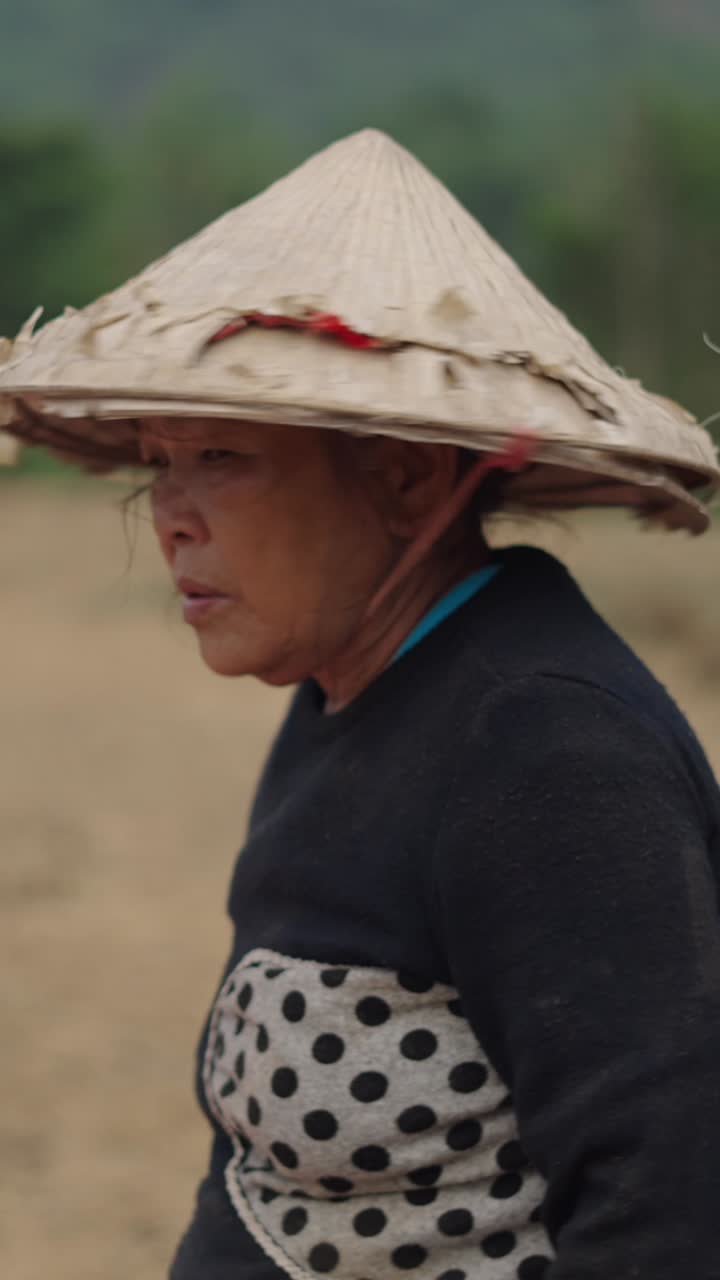 Woman wearing Asian conical hat in a field