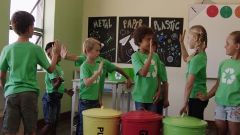 grupo de niños que usan camiseta con símbolo de reciclaje dando los cinco altos entre sí