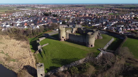 una vista aérea del castillo de rhuddlan en una soleada mañana de primavera, volando de derecha a izquierda alrededor del castillo con la ciudad de rhuddlan al fondo, denbighshire, gales, reino unido