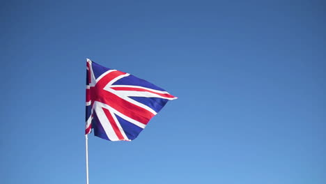 flag of the united kingdom waving in slow motion with clear blue sky in the background