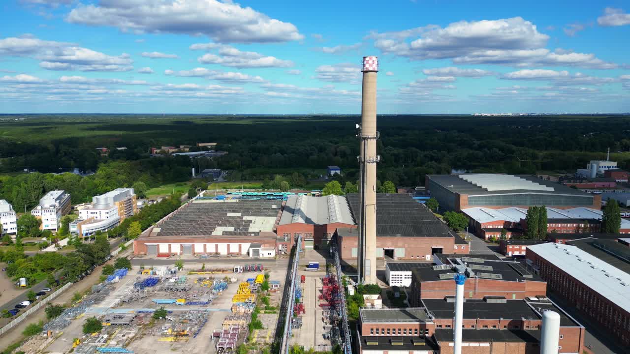 Hennigsdorf steel industry with industrial buildings, chimneys, storage area and a river in the background. Magic aerial view flight pull in drone