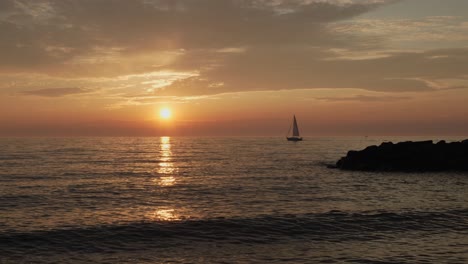 Wide-static-shot-of-a-sailboat-sailing-off-into-the-sunset