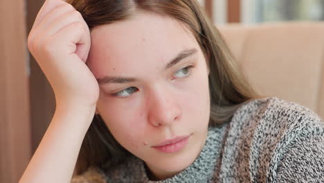 Close up of female intern resting head on hand while seated blinking mindfully with eyes closed showing serene expression in calm indoor setting suggesting moment of thought reflection or quiet pause
