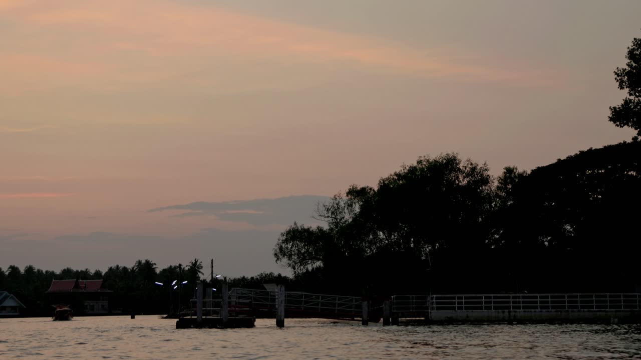저녁에 강변에 있는 집들, 하늘에 부드러운 해가 지는 색조와 함께 조용한 물, 조용한 분위기