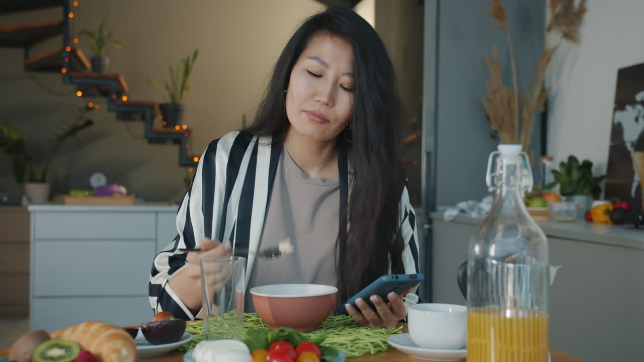 Woman Eating Breakfast and Using a Mobile Phone