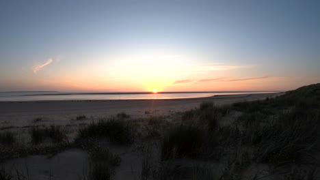 aerial drone footage lifting from the beach and looking at the sun at the horizon of the sea