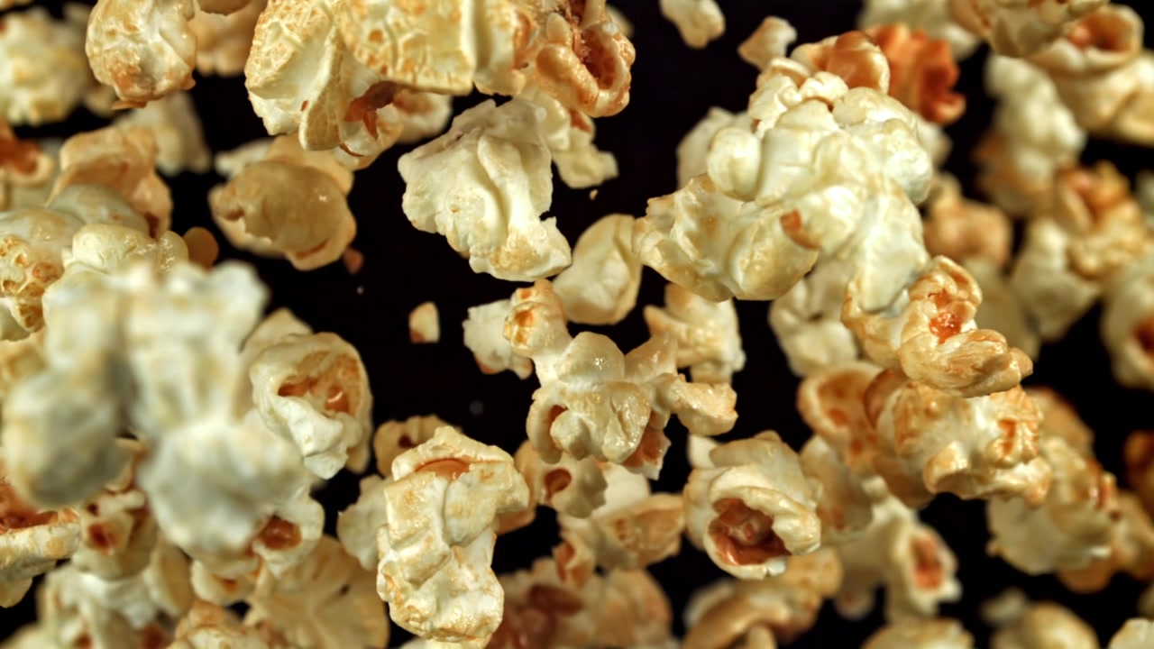Popcorn al burro che cadono al rallentatore su sfondo nero